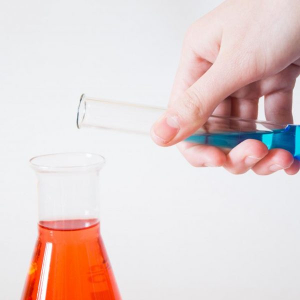 person holding flask pouring to other flask